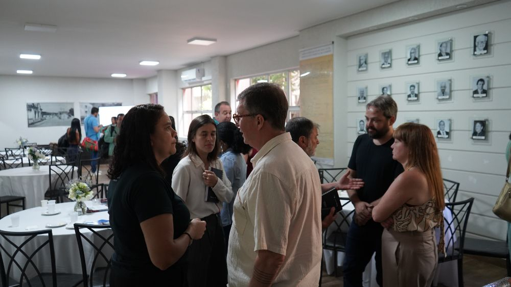 Pessoas conversam de pé em pequenos grupos